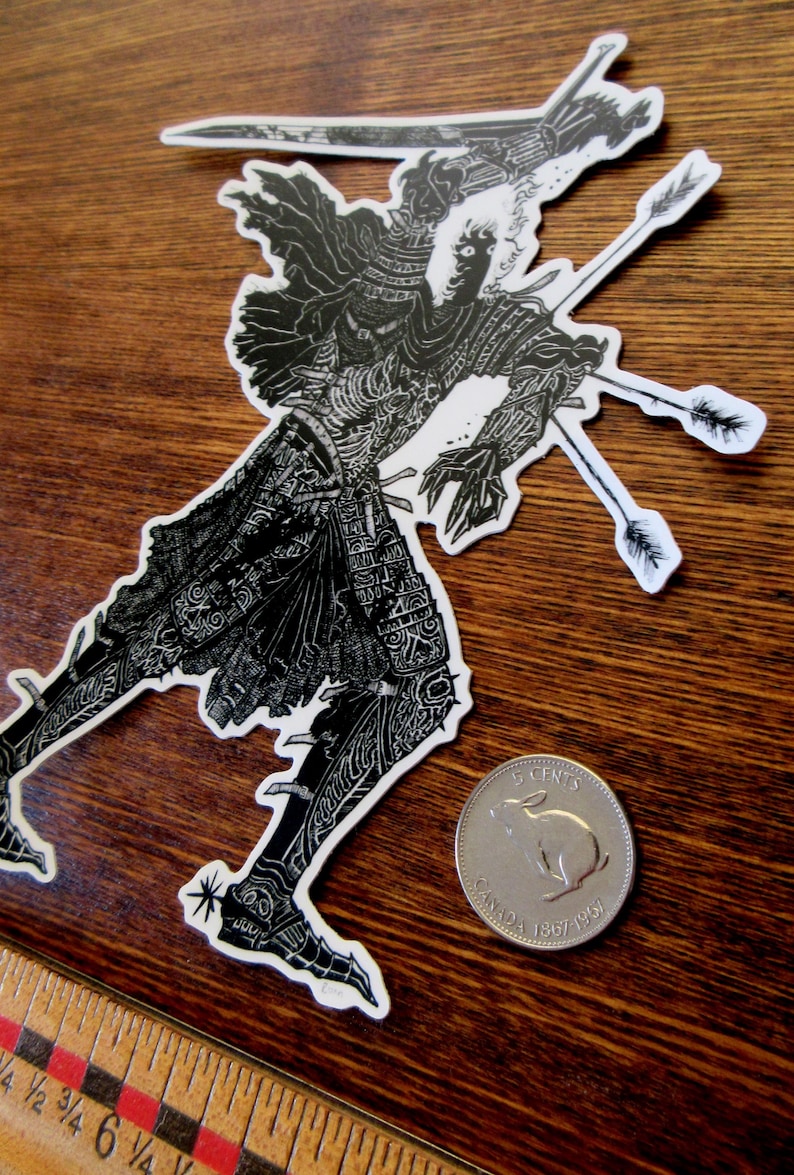 K&ouml;nnte beinhalten: Schwarz-wei&szlig;er Aufkleber mit einer detaillierten Illustration einer Figur, die von Pfeilen durchbohrt wird. Die Figur befindet sich in einer dynamischen Pose, mit komplizierten Mustern auf ihrer Kleidung. Eine kanadische 5-Cent-M&uuml;nze befindet sich neben dem Aufkleber.