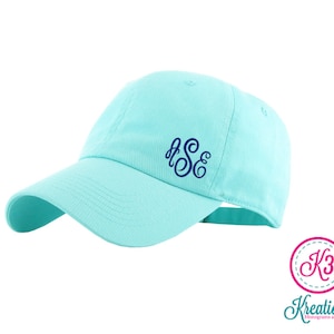 May include: A light blue baseball cap with a navy blue monogram of the letters "S&E" embroidered on the front.