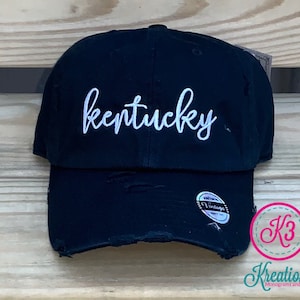 May include: Black distressed baseball cap with white embroidered text that reads "kentucky". The cap has a vintage label on the side.