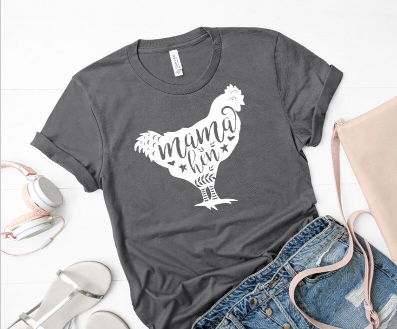 May include: A dark gray t-shirt with a white silhouette of a chicken and the text "mama hen" with stars and leaves.