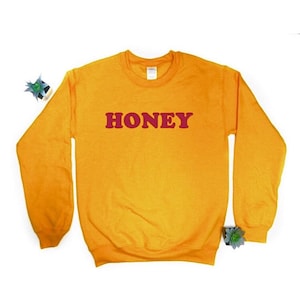 May include: A yellow sweatshirt with the word "HONEY" printed in red on the front.