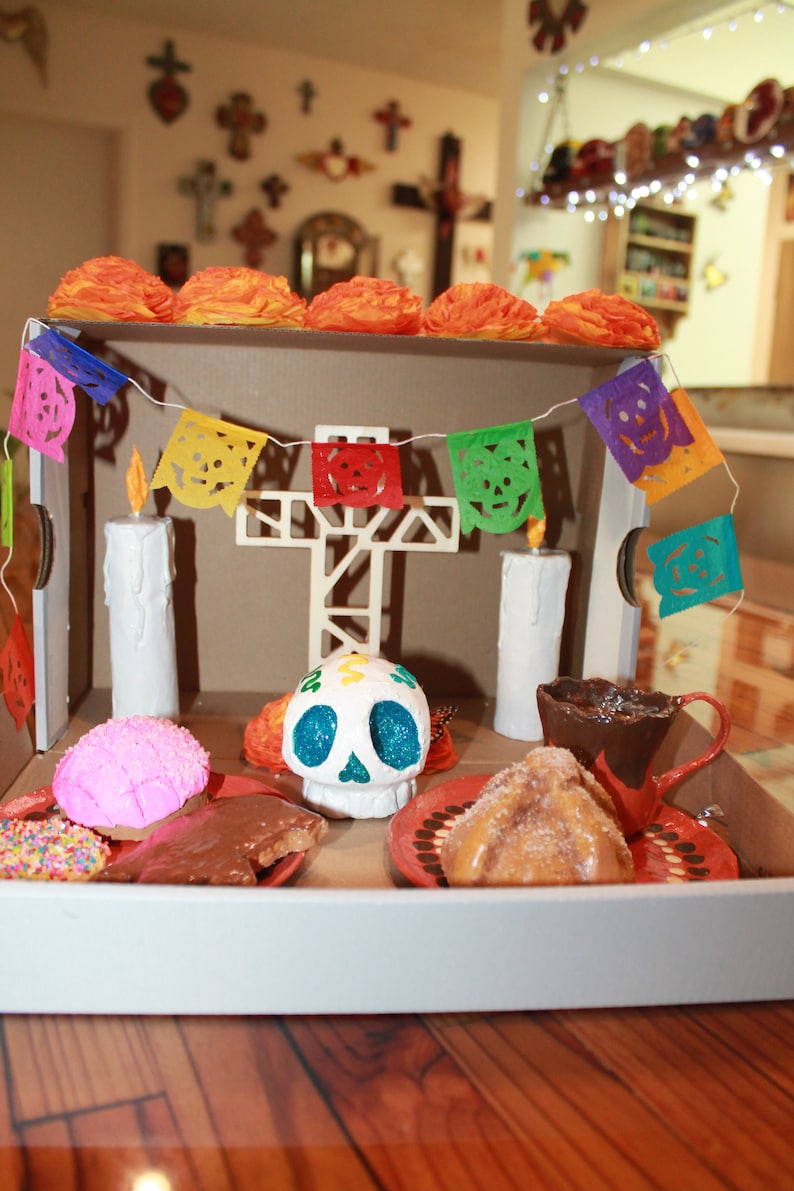 May include: A Day of the Dead altar with a sugar skull, candles, and traditional Mexican treats. The altar is decorated with colorful paper flags and flowers.