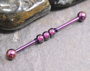 May include: A purple industrial barbell body jewelry piece featuring two spherical end caps and three central beads with a pink and purple marbled pattern, accented by thin dark wire wraps between the beads on the straight metal shaft.