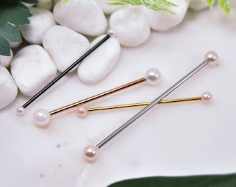 May include: Four industrial barbell piercings with straight metal shafts in black, rose gold, gold, and silver tones. Each barbell features a small spherical bead at one end and a larger, round, white or light pink pearl-like bead at the other end.