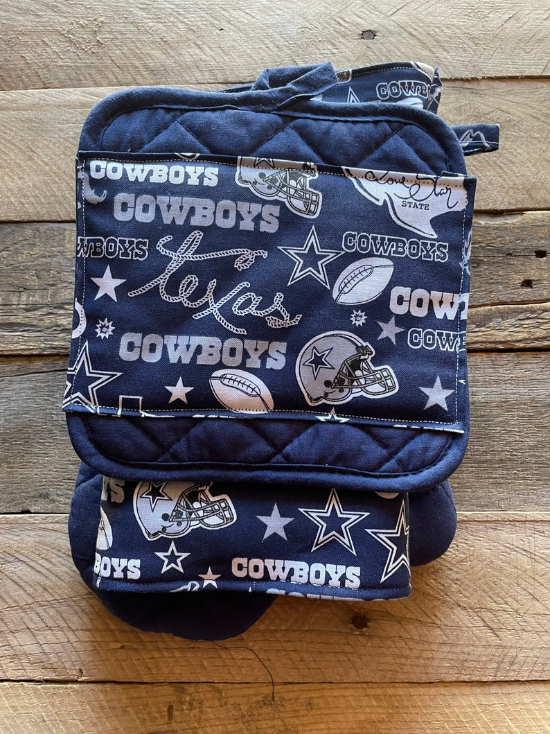 May include: Set of three blue and white oven mitts with a Dallas Cowboys theme. The mitts feature a star, a football, and the words "Cowboys" and "Texas".