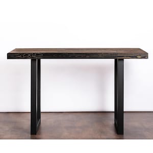 May include: A black wooden console table with a black metal frame. The table has a rectangular top and two legs.