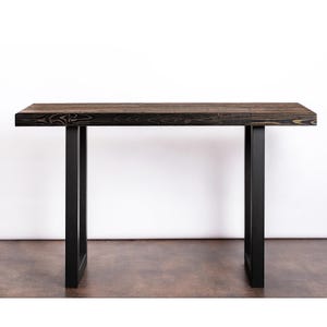 May include: A black wooden console table with a black metal frame. The table has a rectangular top and two legs.