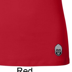 May include: A red short-sleeved t-shirt with a small embroidered image of a Buddha's face on the bottom right corner.