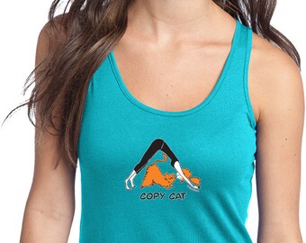 May include: A turquoise tank top with a graphic of a woman doing yoga with a cat copying her pose. The text "COPY CAT" is printed below the graphic.