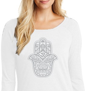 Op de afbeelding: Witte longsleeve met een grijs hamsa hand ontwerp. De hamsa hand is een symbool van bescherming en geluk.