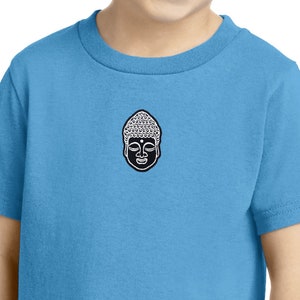 以下が含まれることがあります： 前面に白黒の仏陀のグラフィックが描かれた薄い青色のTシャツです。