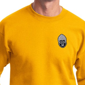 May include: A gold long-sleeved sweatshirt with a small embroidered image of a Buddha's face on the left chest.