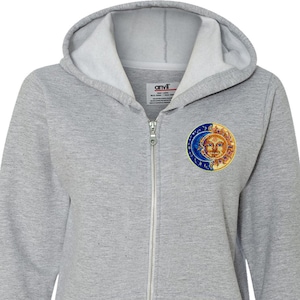 Pode incluir: Um moletom cinza com zíper e um bolso na frente. O bolso tem um design bordado de um sol e uma lua.