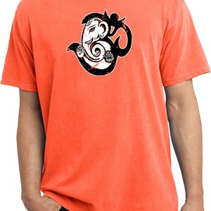 May include: Neon orange t-shirt featuring a distressed black and white graphic of the Hindu deity Ganesha with the Om symbol. The shirt is a short-sleeved crew neck.