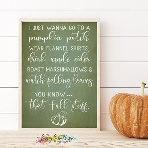 Puede incluir: Un letrero enmarcado con un fondo verde y texto blanco que dice: "Solo quiero ir a un huerto de calabazas, usar camisas de franela, beber sidra de manzana, asar malvaviscos y ver caer las hojas. Ya sabes... esas cosas de otoño". Una gran calabaza naranja está a la derecha.