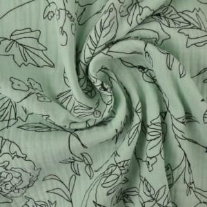 May include: A close-up of a light green fabric with a floral pattern. The design features black outlines of flowers and leaves. The fabric is gathered and folded, creating a textured appearance.