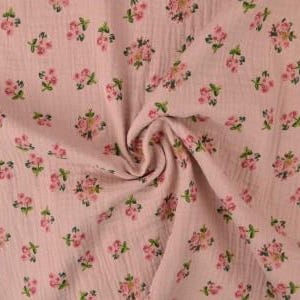 May include: Pink fabric with a floral pattern. The fabric has a crinkled texture and is covered in small clusters of pink flowers with green leaves. The fabric is gathered in a swirl in the center of the image.