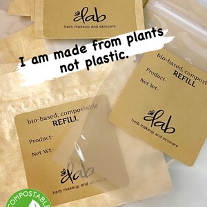 Pu&ograve; includere: Primo piano di un sacchetto di carta marrone con un'etichetta che recita "bio-based, compostable REFILL" e "lab herb makeup and skincare". Il sacchetto &egrave; etichettato "COMPOSTABLE" con un'icona di foglia verde. Il testo "I am made from plants not plastic." &egrave; scritto sul sacchetto.