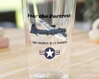 May include: A clear glass pint glass with a graphic of a B-17 bomber plane and the text "Fear the Fortress, The Mighty B-17 Bomber" with a star and stripes design.