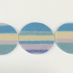 May include: Three circular fabric patches featuring horizontal stripes in shades of light blue, pale yellow, soft lavender, and teal. Each patch has a consistent color pattern with a textured surface, arranged in a row against a plain background.