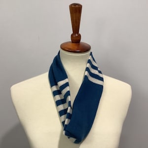 May include: A teal blue and white striped scarf on a white mannequin.