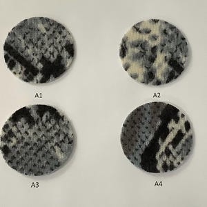 May include: A set of three ceramic mugs with a speckled, matte finish. The mugs are in shades of cream, light gray, and dark gray. Each mug has a simple, minimalist design and a rounded handle.