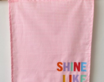 Fabric wall banner hanging with iridescent and spotty wording.