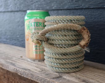 Könnte beinhalten: Ein zylindrischer Getränkehalter aus gewickeltem, hellblauem Seil mit einem dicken, strukturierten Seilgriff an der Seite. Neben dem Halter steht eine grüne Aluminiumdose mit der Aufschrift Watermelon Waterloo Sparkling Water.