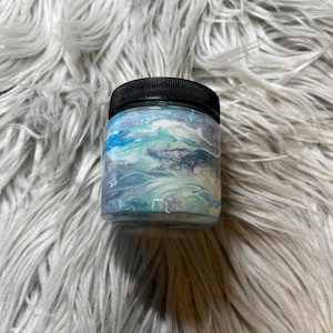 May include: A small glass jar with a black lid. The jar is filled with a blue, white, and gray marbled paint.
