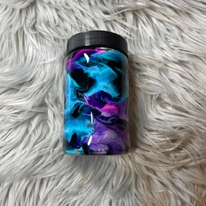 May include: A black jar with a clear glass body and a black lid. The jar is decorated with a swirling pattern of blue, purple, and pink paint.