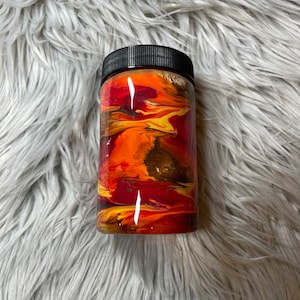 May include: A black and orange tumbler with a swirling abstract design. The tumbler has a black lid and is made of stainless steel.