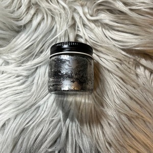 May include: A small glass jar with a black lid filled with silver glitter.
