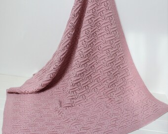May include: A soft, pink knitted baby blanket with a delicate openwork pattern.