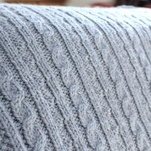 Cabled baby blanket knitting pattern. This completely reversible blanket has cables on both sides of the blanket. The moss stitch edges are knitted at the same time. Pattern written for Aran weight yarn.
