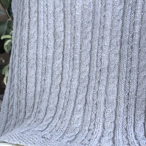 Cabled baby blanket knitting pattern. This completely reversible blanket has cables on both sides of the blanket. The moss stitch edges are knitted at the same time. Pattern written for Aran weight yarn.