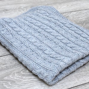Cabled baby blanket knitting pattern. This completely reversible blanket has cables on both sides of the blanket. The moss stitch edges are knitted at the same time. Pattern written for Aran weight yarn.