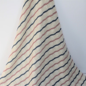 May include: A striped knitted baby blanket in shades of pink, blue, and white.