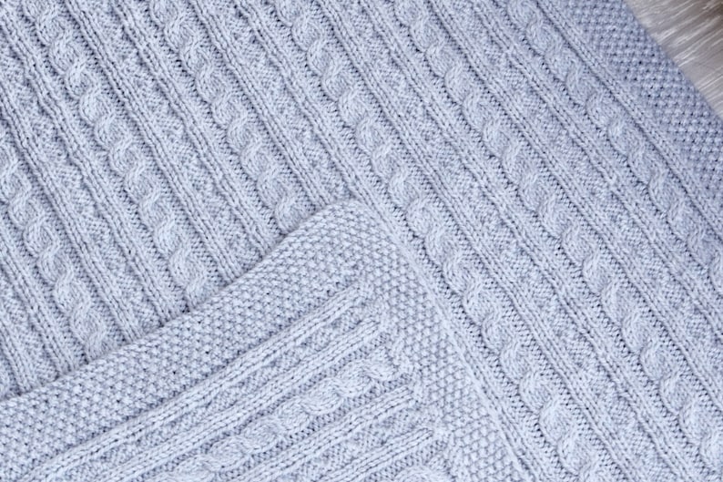 Cabled baby blanket knitting pattern. This completely reversible blanket has cables on both sides of the blanket. The moss stitch edges are knitted at the same time. Pattern written for Aran weight yarn.