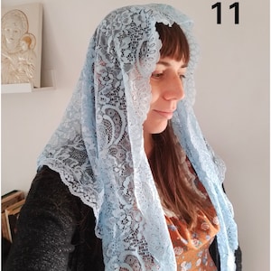 May include: A light blue lace mantilla with a floral pattern. The mantilla is worn by a person with brown hair. The number 11 is visible in the top right corner of the image.