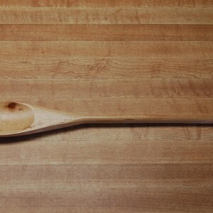 May include: A wooden spoon with a rounded bowl and a long handle.