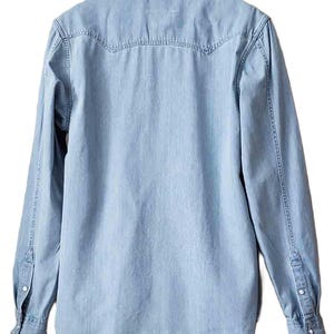 Puede incluir: Camisa vaquera azul claro de manga larga. La camisa presenta un cuello cl&aacute;sico, pu&ntilde;os abotonados y un detalle de canes&uacute; en la espalda. La mezclilla tiene un aspecto descolorido.