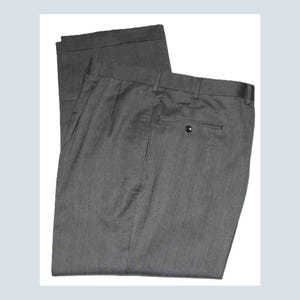 May include: A pair of charcoal gray trousers featuring a pleated front, a waistband with belt loops, and a single rear pocket with a button closure. The fabric has a subtle vertical texture, and the legs are finished with a cuffed hem at the bottom.