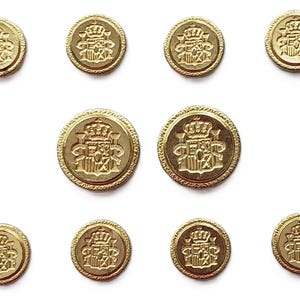 May include: A collection of ten round gold-colored metal buttons arranged in three rows. Each button features a raised embossed design of a heraldic coat of arms topped with a crown, surrounded by a textured border along the outer edge.