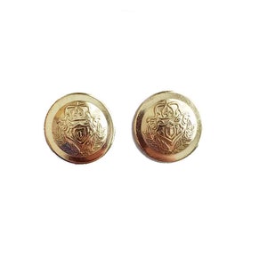 May include: Two gold-colored metal buttons with a detailed crest design featuring a crown, shield, and laurel leaves. The buttons are round and have a shiny finish, suitable for coats or jackets.