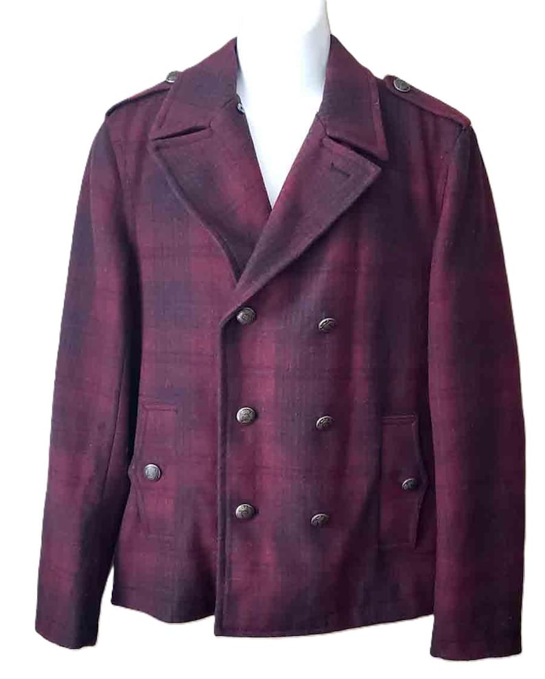 K&ouml;nnte beinhalten: Burgunderfarbene, zweireihige Jacke mit Karomuster. Die Jacke hat sechs dunkle Metallkn&ouml;pfe, zwei Vordertaschen und Schulterklappen. Die Jacke wird auf einer wei&szlig;en Schaufensterpuppe pr&auml;sentiert.
