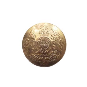 May include: A vintage brass button with an embossed design. The button features a detailed coat of arms with a crown, lion, and unicorn. The button is round and has a slightly aged appearance, suggesting it is antique or vintage.