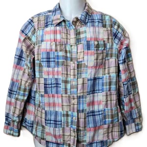 May include: A long-sleeve button-down shirt featuring a patchwork design composed of various plaid fabric squares in shades of blue, pink, tan, and white. The shirt includes a standard collar, a front button placket, and two chest pockets.