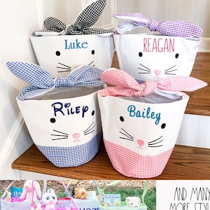 May include: Four personalized Easter baskets with bunny faces and gingham bows. The baskets are in blue, pink, purple, and black gingham. The names Luke, Reagan, Riley, and Bailey are embroidered on the baskets.