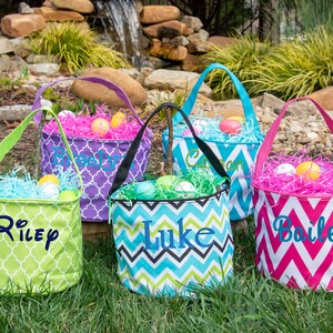 May include: Four personalized Easter baskets with different colored chevron and geometric patterns. The baskets are filled with shredded paper and plastic Easter eggs. The names Riley, Luke, Bailey, and Carson are embroidered on the baskets.