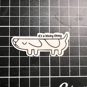 May include: A black and white line drawing of a dog with the text "it's a bluey thing" above it.